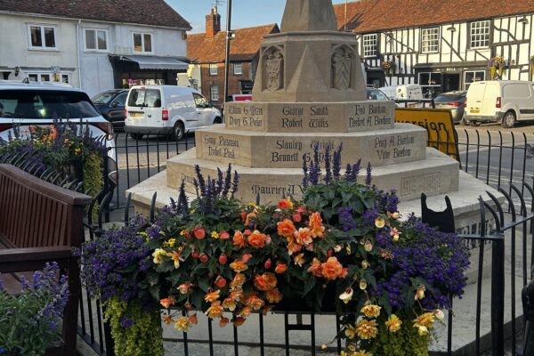 Town monument with a colorful flower display at its base in a village square.